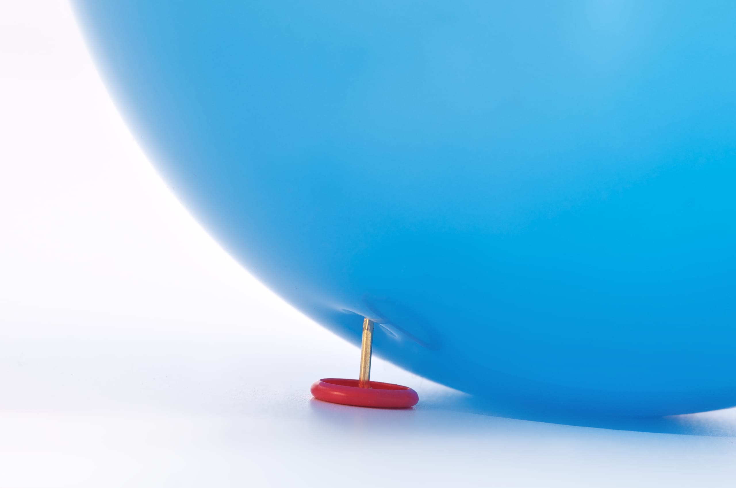 Tack pressing against a blue balloon